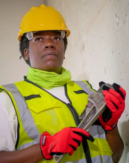 Licensed Halsted plumber in a hard hat and safety vest holding a pipe wrench